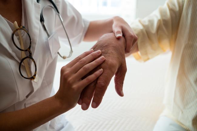 Fotografía de una doctora examinando la mano de un paciente.