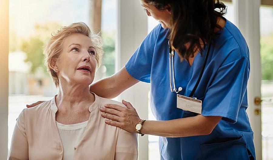 Foto de un proveedor de atención médica sonriendo mientras habla con un adulto mayor