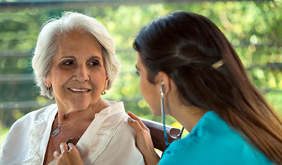 Foto de una médica que ausculta el corazón de un paciente mayor