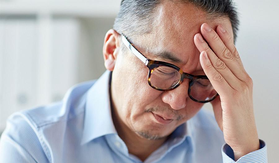 Imagen de un hombre con la mano en la frente por el dolor.