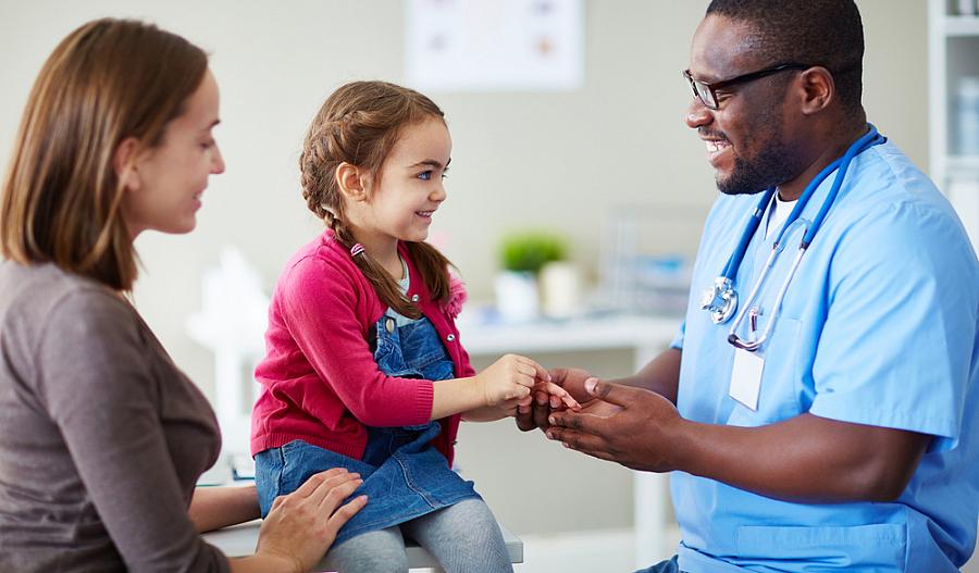 Foto de una niña y su madre hablando con un médico en una clínica