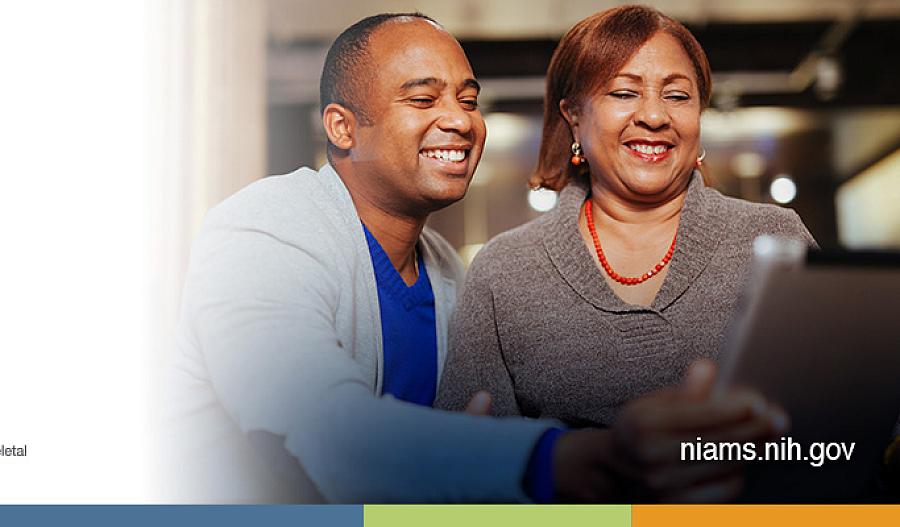 Dos adultos sonrientes mirando una computadora.