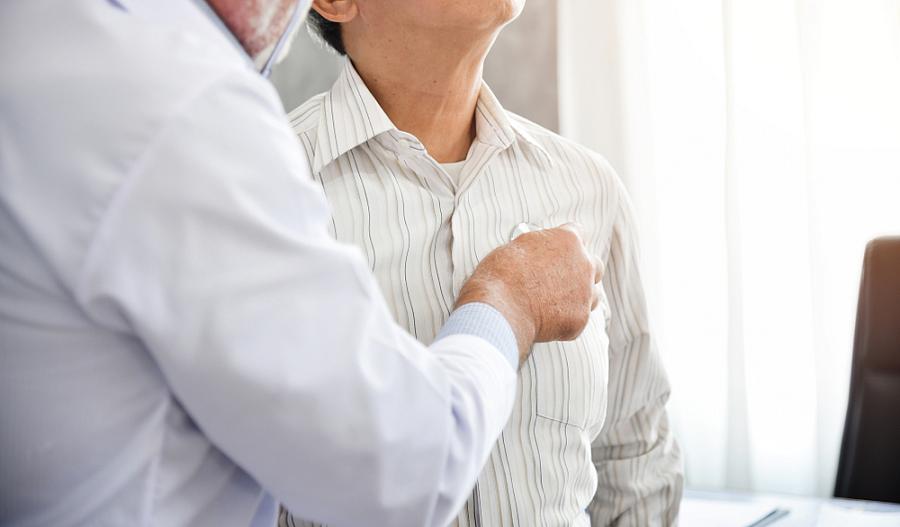 Imagen de un médico que ausculta el tórax de un paciente mayor con un estetoscopio.