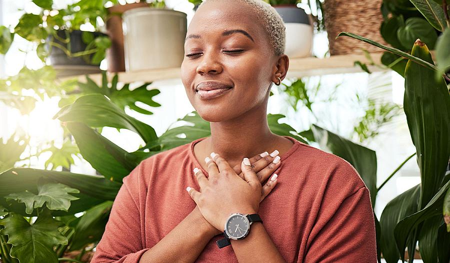 Imagen de una joven meditando entre plantas de interior