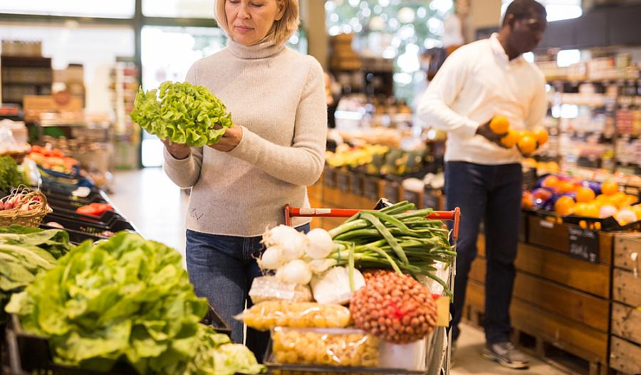 Fotografía de una mujer de mediana edad comprando verduras frescas.